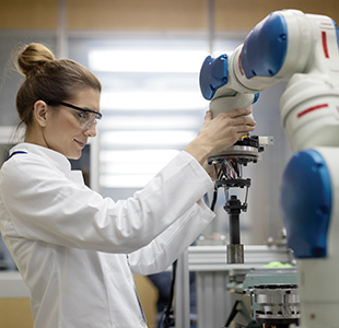 Female laboratorian using a robotic arm in a lab