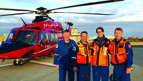Four healthcare workers standing in front of a helicopter ambulance 