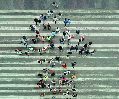 A birds-eye view of people walking and forming the shape of an arrow pointing up