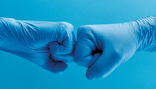 Two gloved hands together in front of a blue background.