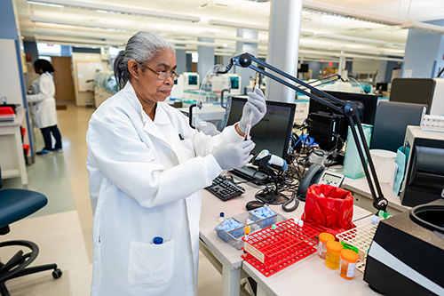 A Black, woman laboratorian holding a pipette and a test tube.