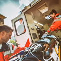 Emergency Medical Technicians lift a patient on a stretcher out of an ambulance